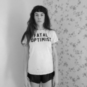 A black & white image of a woman stood in the corner of a room